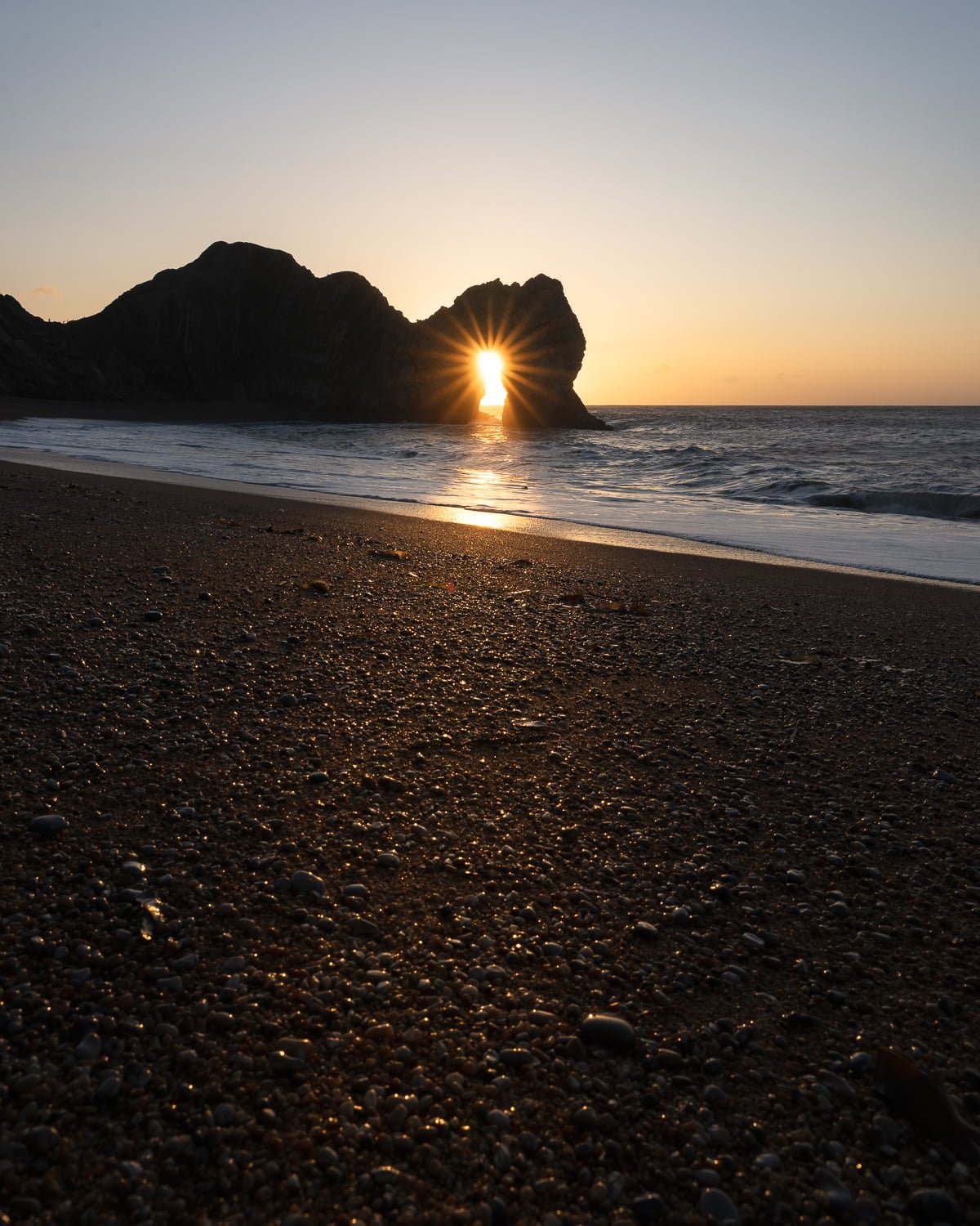 durdle door sunrise through arch