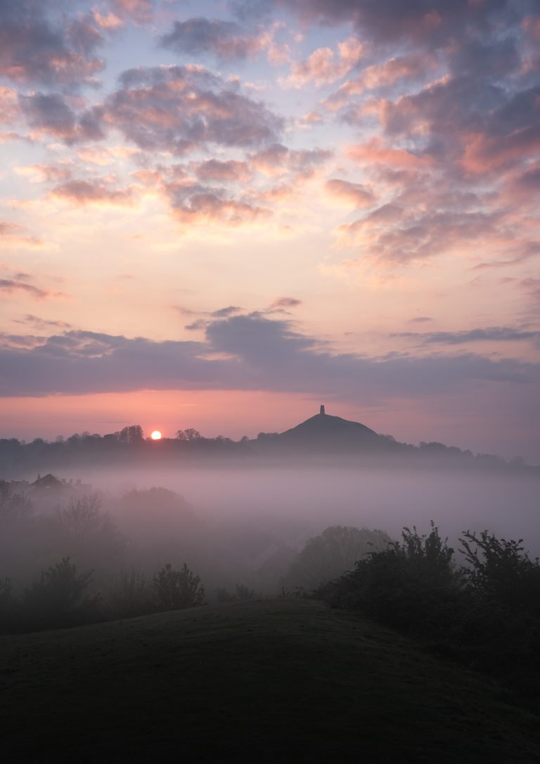 A beautiful pastel-coloured misty sunrise looking towards Glastonbury Tor